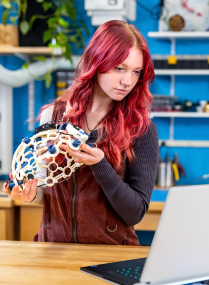 Jessica Howard looking at a computer and holding a research device.